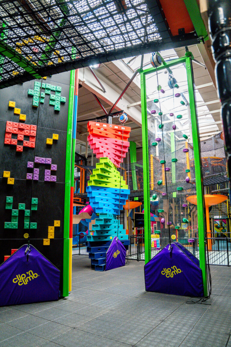 Eine Fläche mit mehreren bunten verschiedenen Kletterstationen, welche alle bis unter die Hallendecke des Indoor Freizeitparks gehen.
