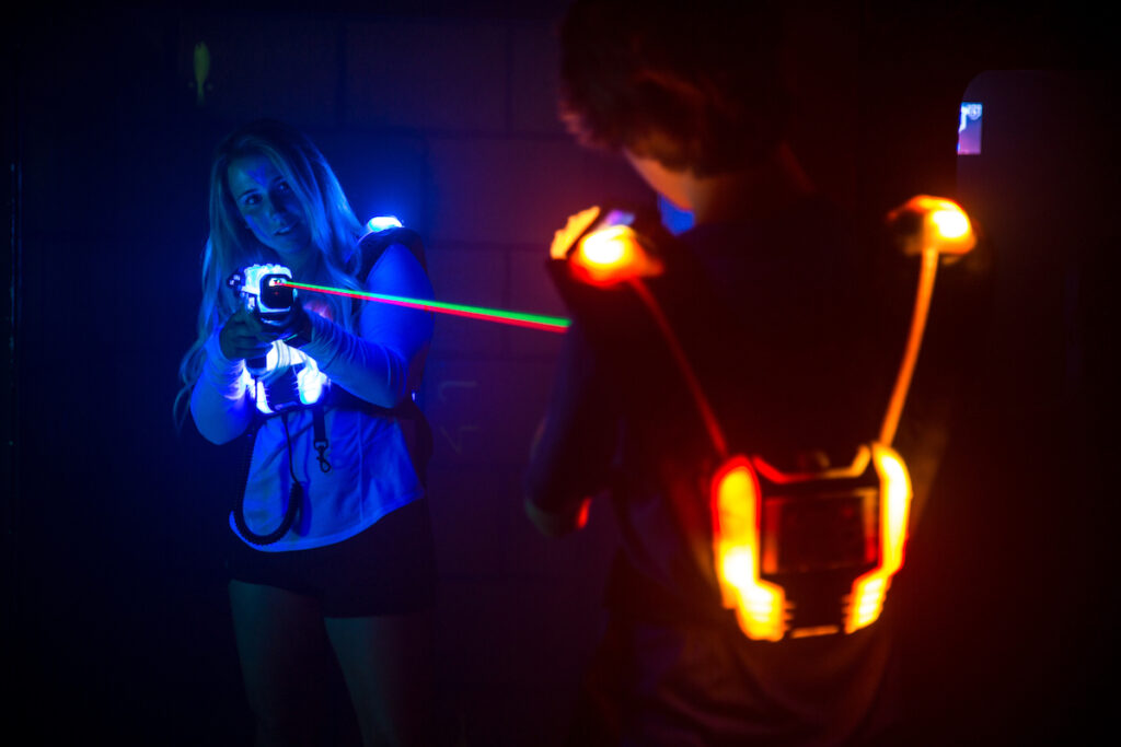 Eine Frau spielt Lasertag und zielt auf eine weitere Person, welche auch Lasertag in der Lasertag Arena der MAXX Arena in Kirchheim spielt.