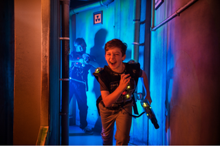 Ein kleiner Junge rennt einen dunklen Gang entlang und hält einen Laserball Phaser in der Hand.
