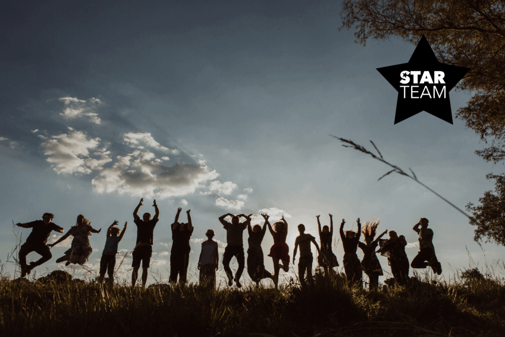 Eine große Gruppe springt in die Luft, es dämmert bereits. Es sind lediglich die Staturen zu sehen, der Himmel ist bereits dunkel.