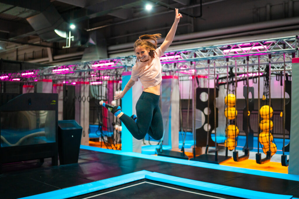 Es ist eine Frau zu sehen, welche bei einer Freitag Abend Aktivität eine Trampolin-Luftfigur macht.