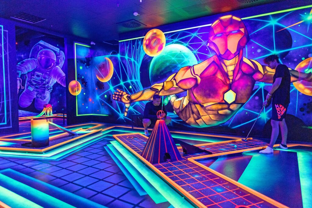 Bei der 3D Blacklight Golf Spielbahn handelt es sich um das Thema Universum, darum ist ein großer Astronaut auf die Wand gezeichnet.