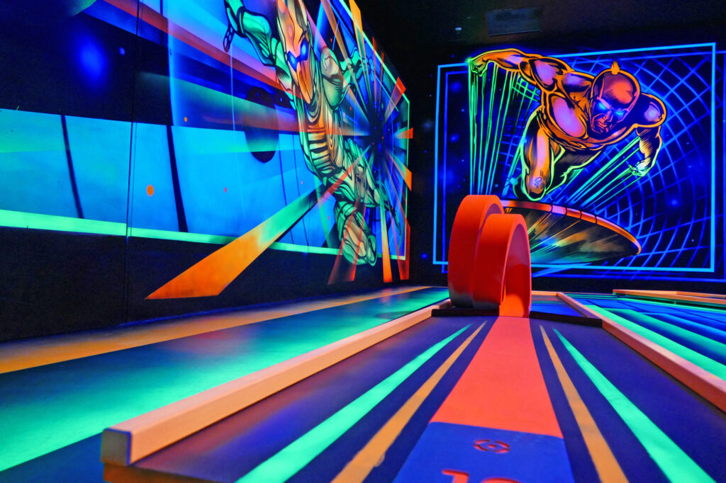 Bei der 3D Blacklight Golf Spielbahn handelt es sich um das Thema Superheld. An der Wand sind Superhelden abgebildet, welche ebenso in Neonfarben leuchten.