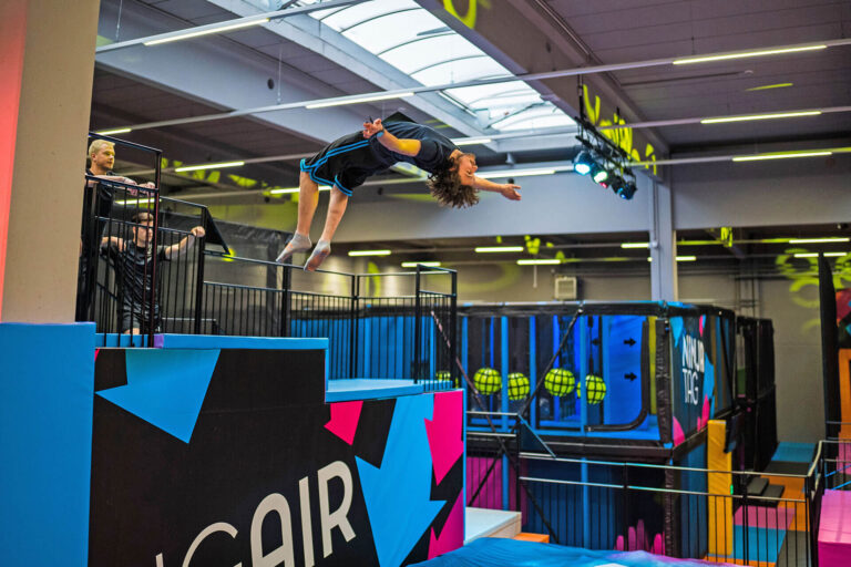 Ein Mann macht einen Salto in der Luft und springt in einen Airbag, welcher zwei bis drei Meter in der Höhe ist.