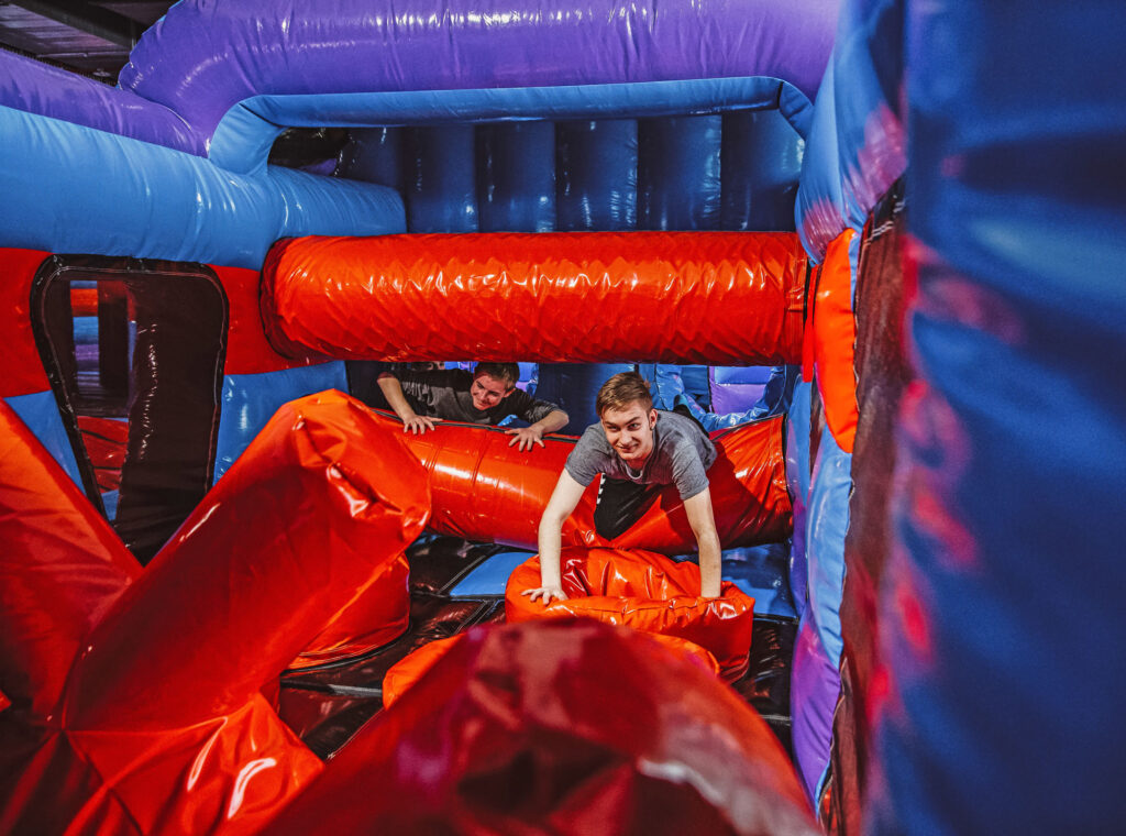 Zwei Jungs kämpfen sich durch einen Inflate Ninja Parcours, welcher rot und blau gefärbt ist.