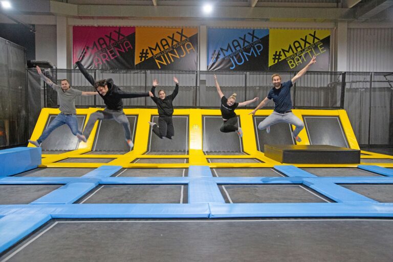 Fünf Mitarbeiter der MAXX Arena springen motiviert, bei einem Team Event, auf Trampolinen mit Posen in die Luft.