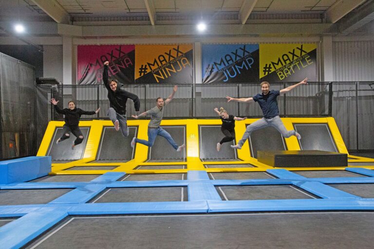 Fünf Mitarbeiter der MAXX Arena springen motiviert, bei einem Team Event, auf Trampolinen mit Posen in die Luft.